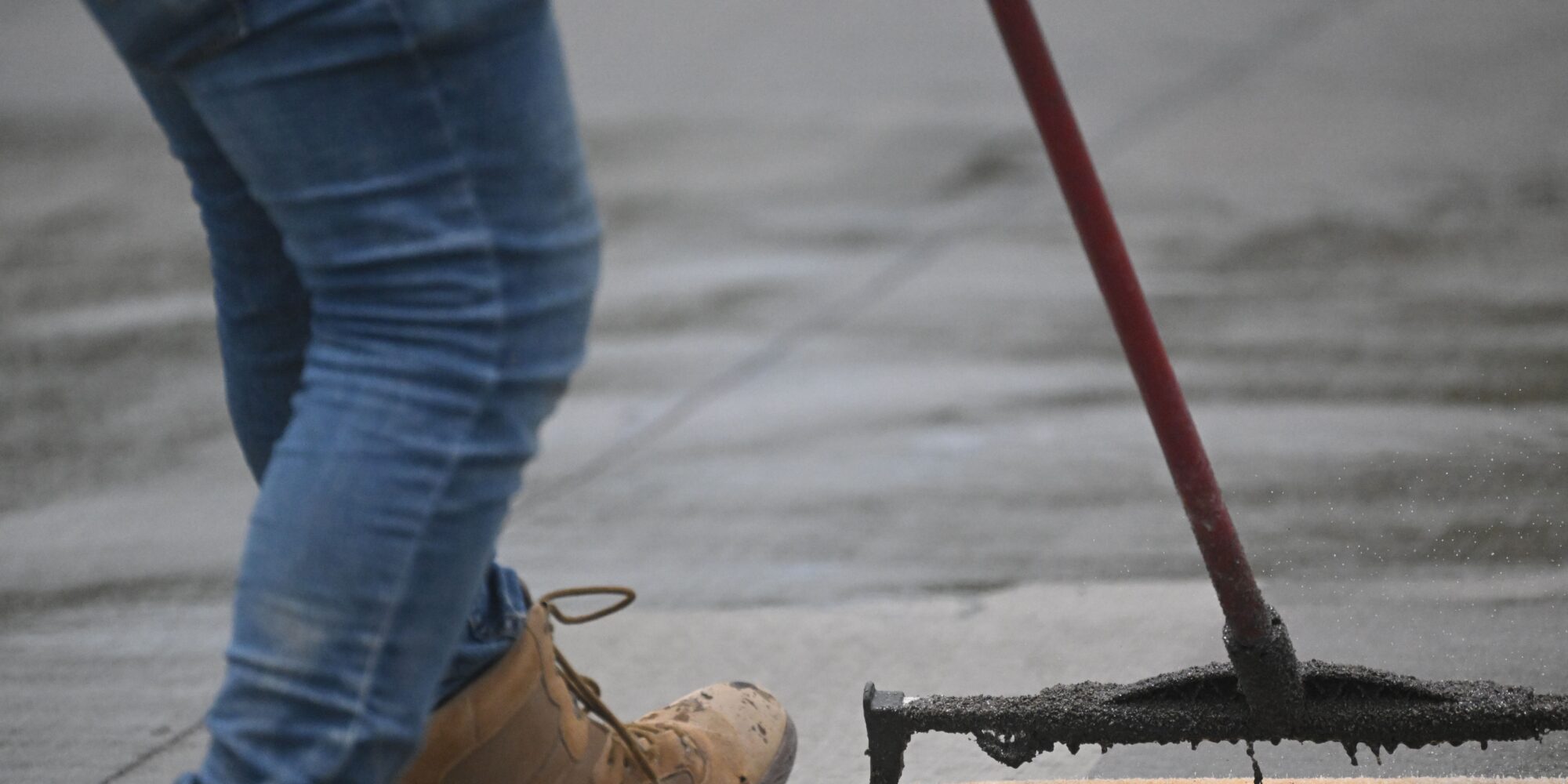 En hantverkare som rollar på en permanent ytförstärkare och densifierare för att dammbinda ett betonggolv.
