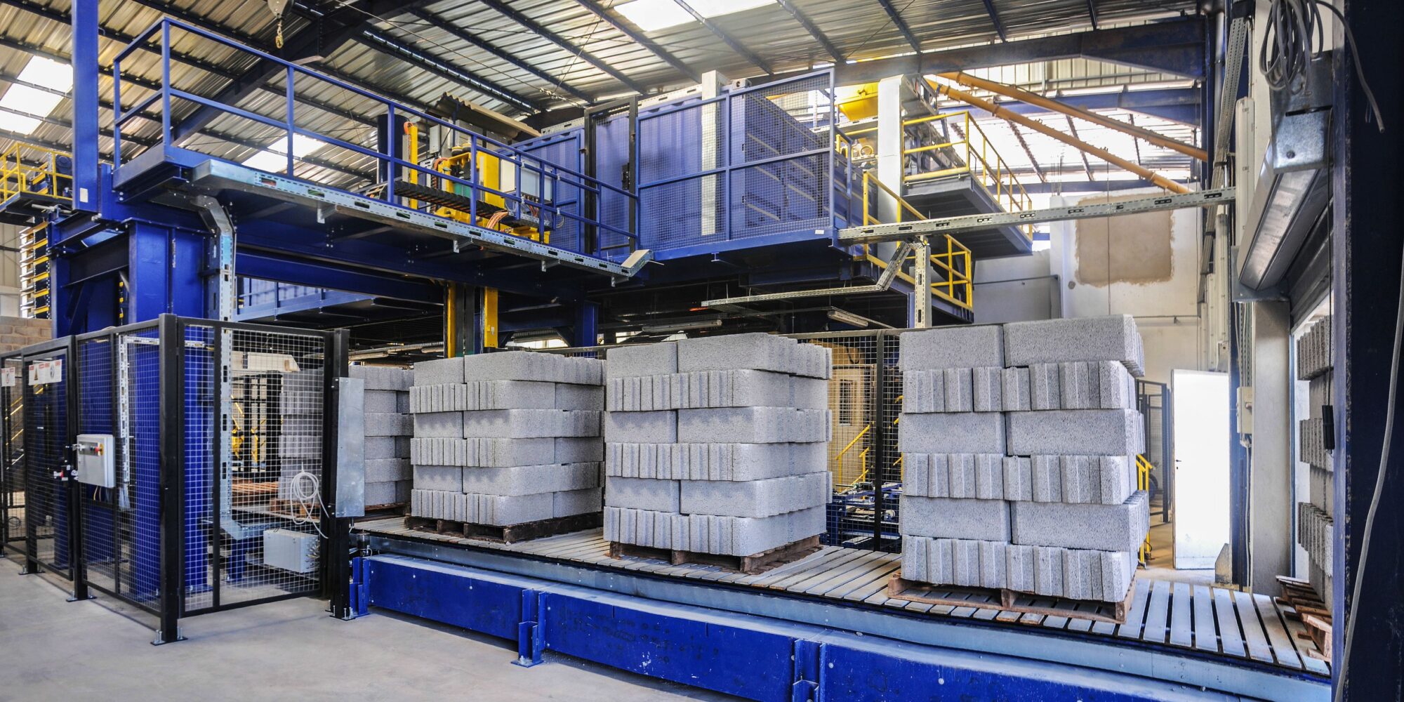 En modern produktionsanläggning med tunga maskiner och betongblock som visar en krävande miljö för Husqvarna Superfloor.