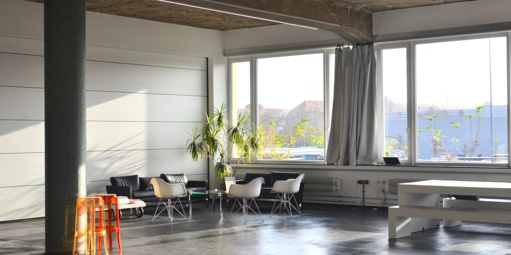 Ett slätt och modernt polerat betonggolv i en renoverad industrilokal med rått betongtak och stora fönster.