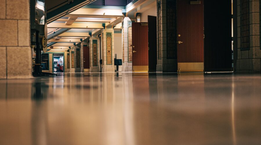 Ett blankt, tåligt och dammfritt betonggolv i en korridor i en offentlig byggnad eller skola efter golvbehandling.