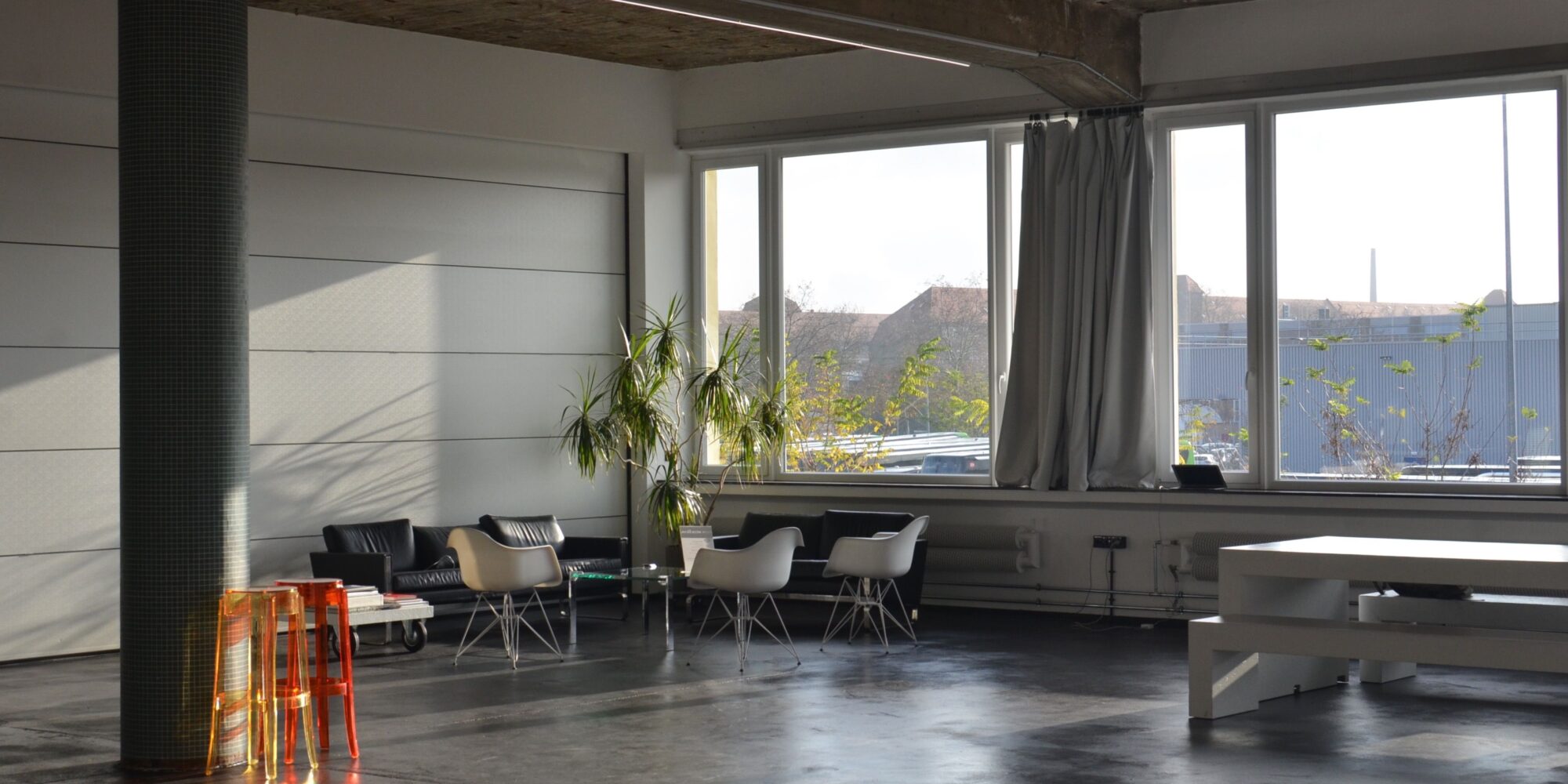 Solljus strömmar in över ett exponerat betonggolv i en modern fastighet, vilket illustrerar betongens termiska massa och ljusreflektion.