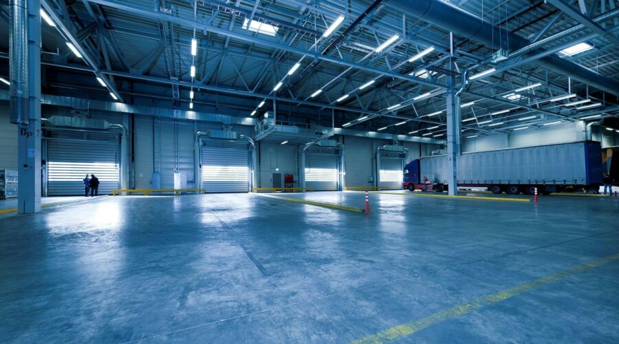 Ett rent och polerat betonggolv i en modern industrilokal med lastbilsportar där dagsljuset strömmar in.