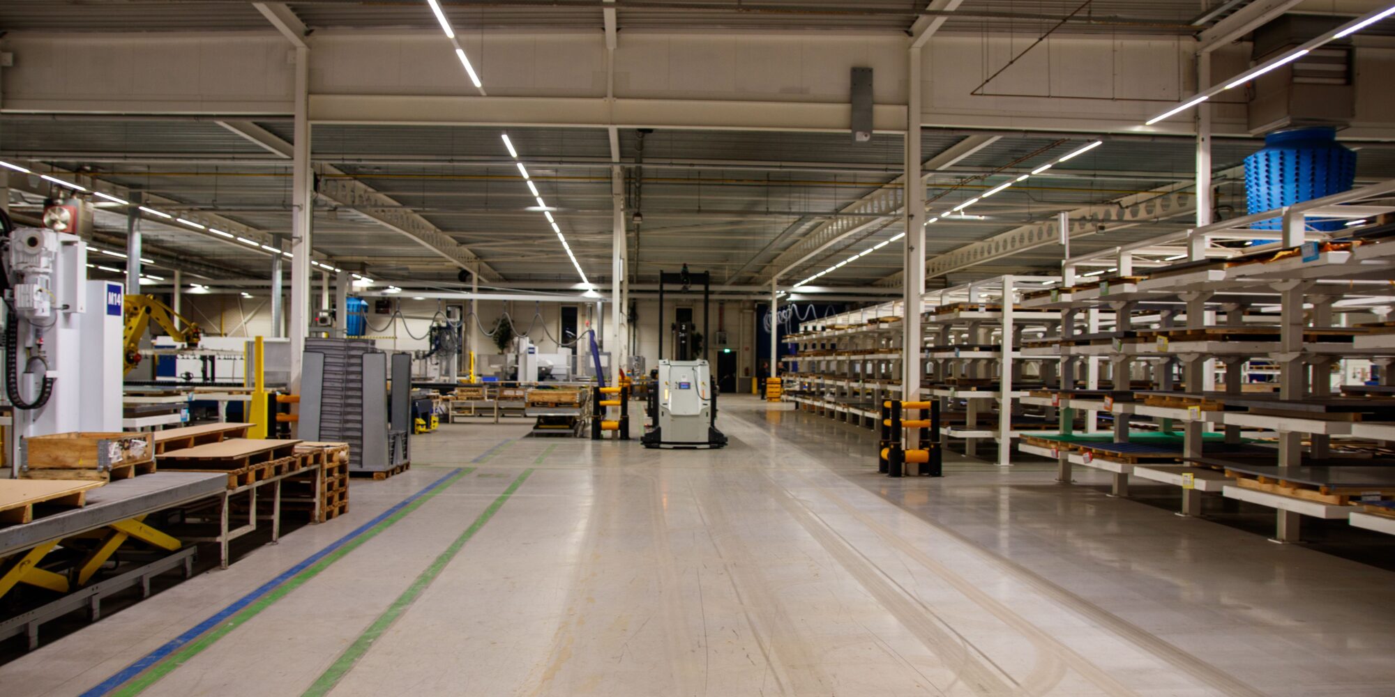 Ett ljust och polerat betonggolv i en modern industrilokal där en självkörande AGV-robot kör i gången.