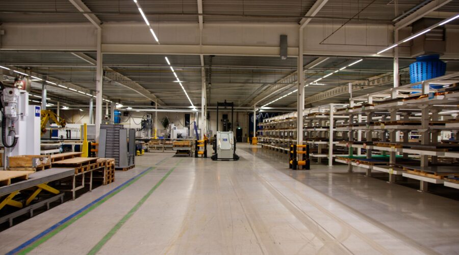 Ett ljust och polerat betonggolv i en modern industrilokal där en självkörande AGV-robot kör i gången.