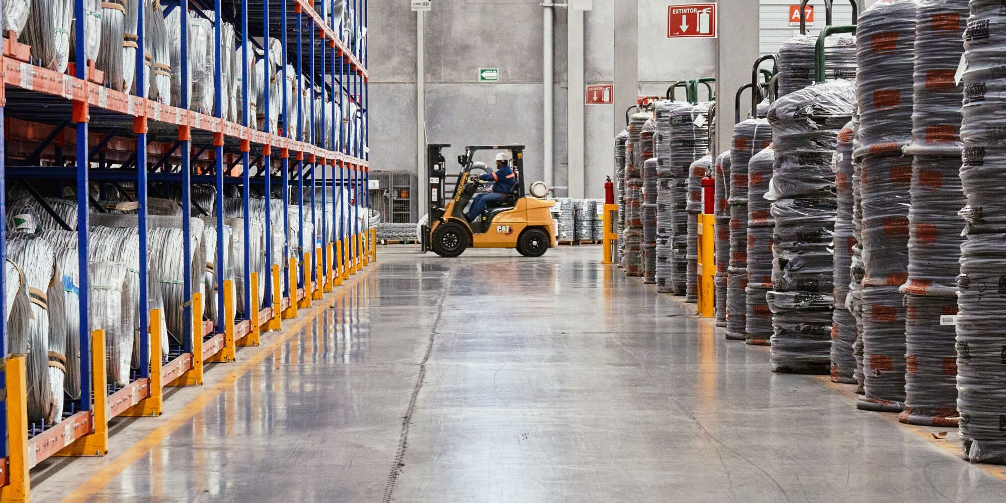 Ett nyrenoverat och jämnt betonggolv i en stor lagerlokal där en gaffeltruck kör mellan pallställage.
